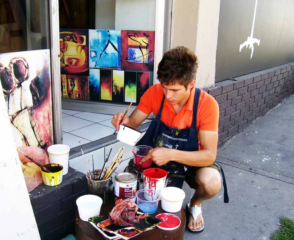 Ivan Guaderrama painting in his early years outside his first studio, mixing colors on the sidewalk